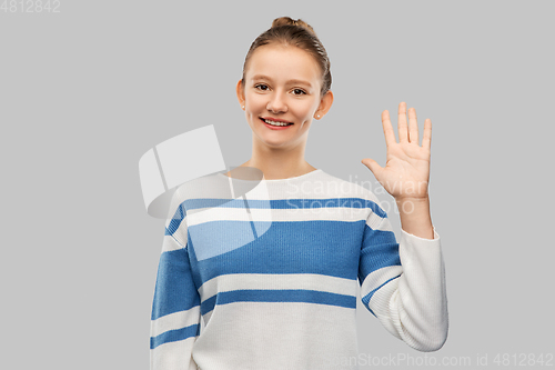 Image of smiling teenage girl in pullover waving hand