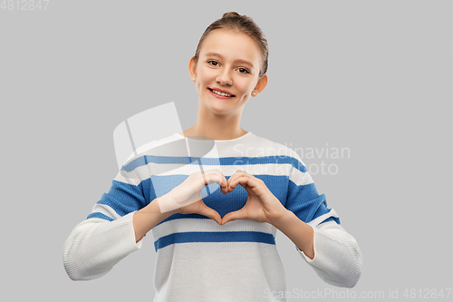 Image of smiling teenage girl making hand heart