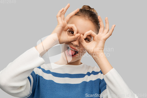 Image of funny teenage girl looking through finger glasses