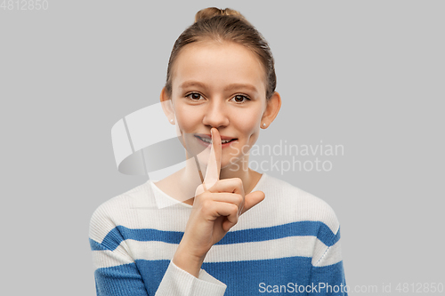 Image of smiling teenage girl with finger on lips