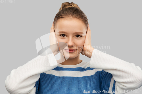 Image of teenage girl closing ears by hands