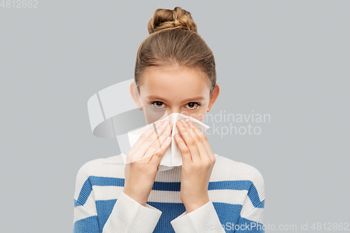 Image of sick teenage girl blowing nose with paper tissue