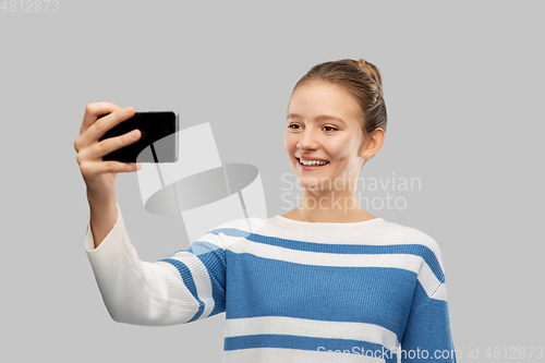 Image of smiling teenage girl taking selfie with smartphone