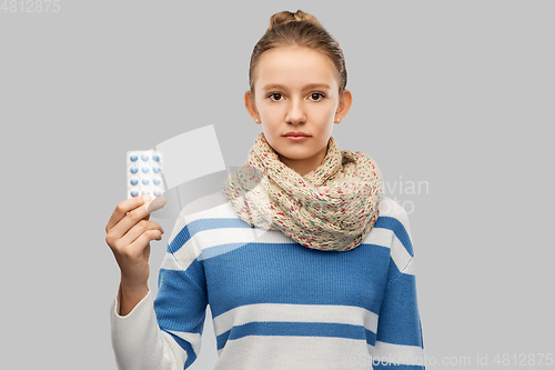 Image of sick teenage girl in scarf with medicine pills