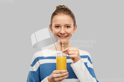 Image of smiling teenage girl holding glass of orange juice