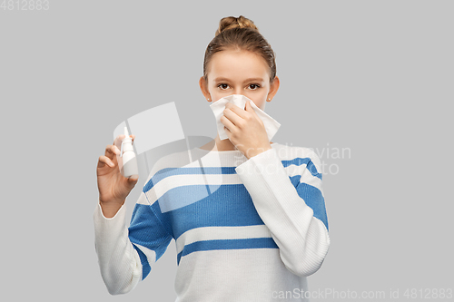 Image of sick teenage girl with nasal spray blowing nose