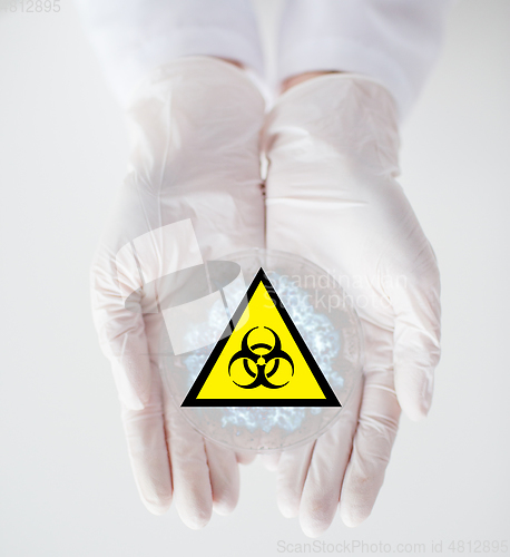 Image of hands with test sample and boihazard caution sign