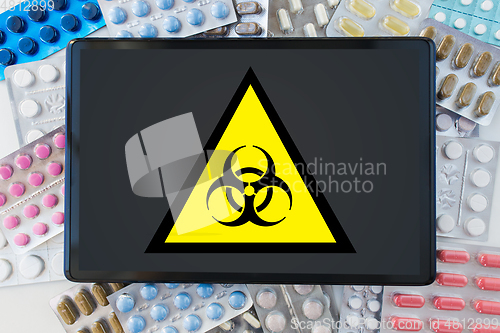 Image of boihazard caution sign, tablet pc and drugs