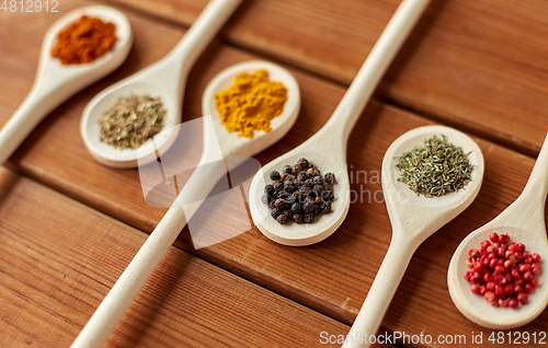 Image of spoons with different spices on wooden table