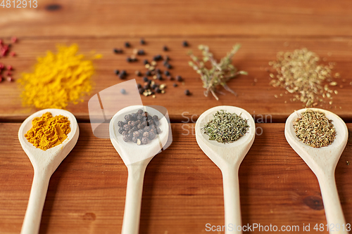 Image of spoons with different spices on wooden table