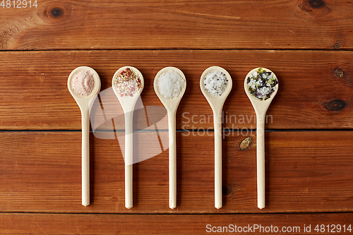 Image of spoons with salt and spices on wooden table