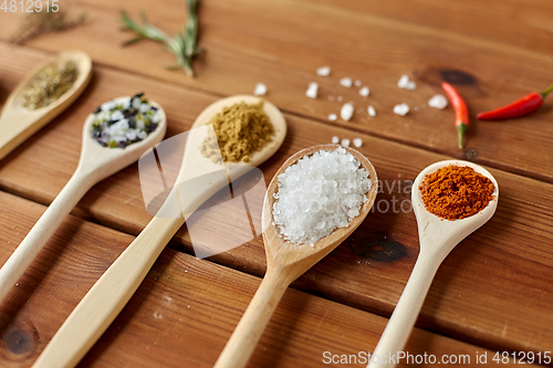 Image of spoons with spices and salt on wooden table