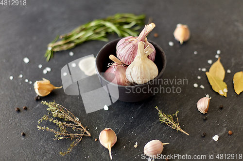 Image of garlic in bowl and rosemary on stone surface