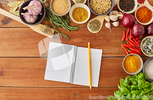 Image of notebook with pencil among spices on wooden table