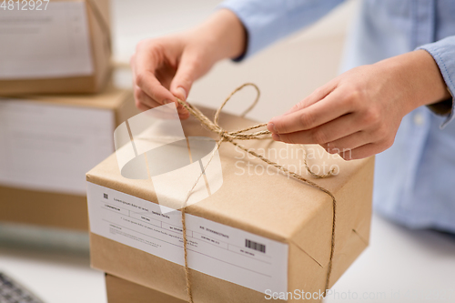 Image of woman packing parcel and tying rope at post office