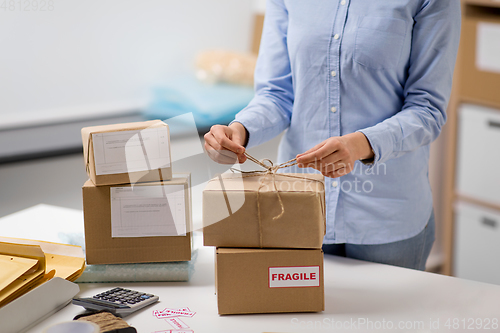 Image of woman packing parcel and tying rope at post office