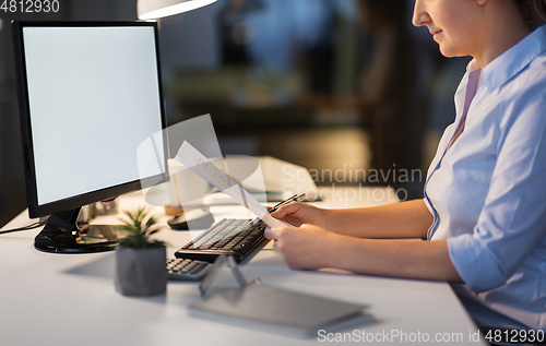 Image of businesswoman with papers working at night office