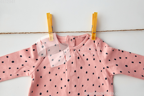 Image of pink shirt for baby girl hanging on rope with pins