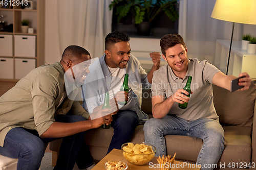 Image of male friends with smartphone taking selfie at home