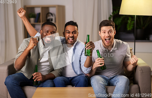 Image of happy male friends or fans drinking beer at home