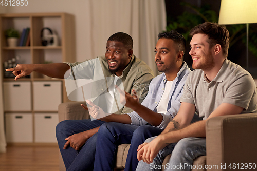 Image of male friends watching tv and talking at home