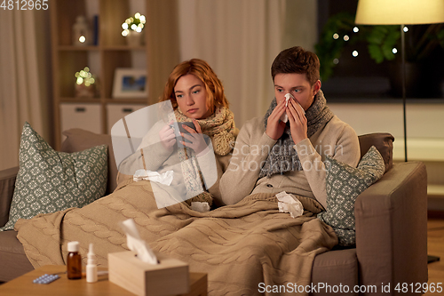 Image of sick young couple drinking hot tea at home
