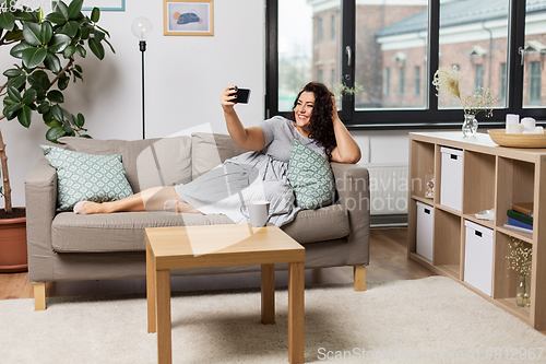 Image of happy woman taking selfie with smartphone at home