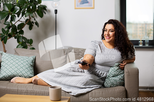 Image of woman with remote control and watching tv at home