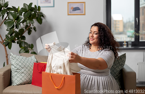 Image of happy young woman with shopping bags at home