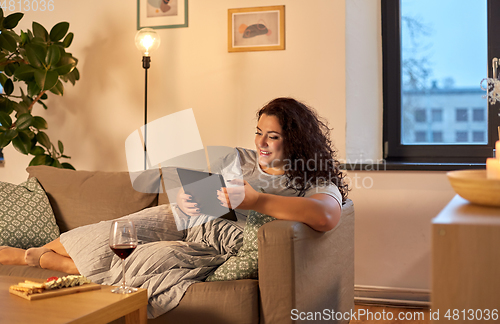 Image of woman with tablet pc, red wine and snacks at home