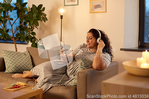 Image of woman in headphones listens to music on smartphone