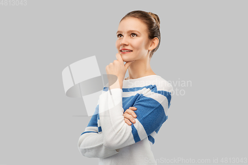 Image of smiling teenage girl in pullover thinking