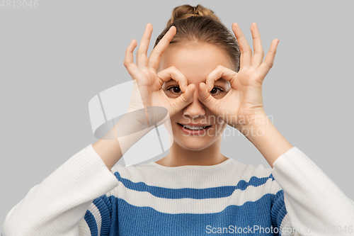 Image of teenage girl looking through finger glasses