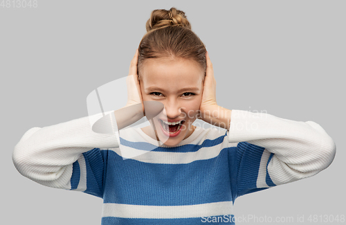 Image of teenage girl closing ears by hands and screaming