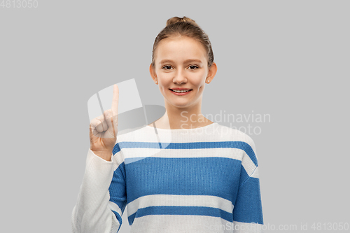 Image of happy teenage girl in pullover pointing finger up