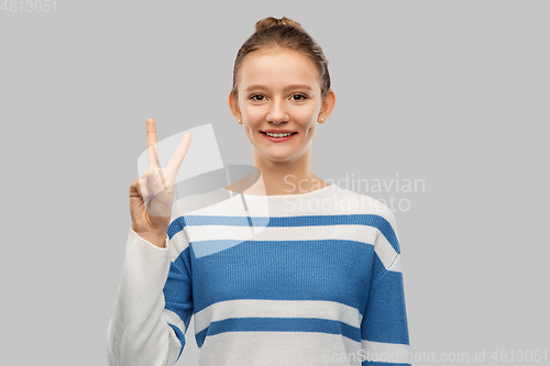 Image of smiling teenage girl showing peace hand sign