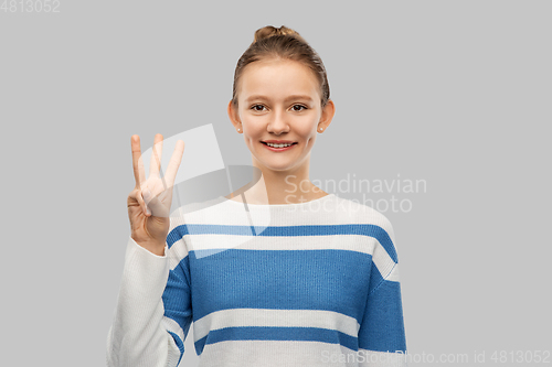 Image of smiling teenage girl showing three fingers