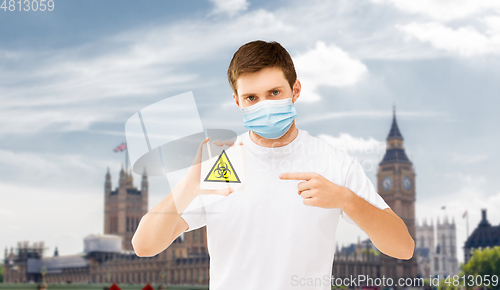 Image of man in medical mask with biohazard sign in england