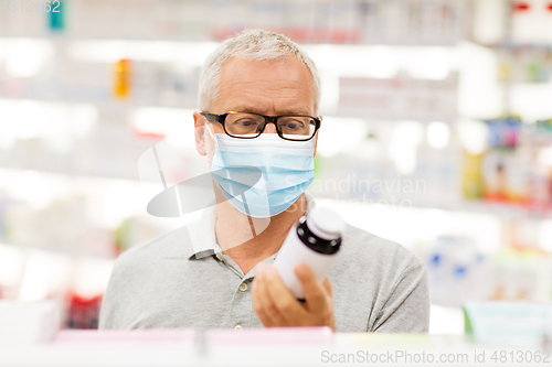 Image of senior man in medical mask with drug at pharmacy