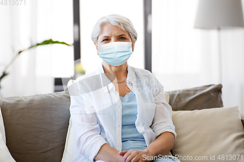 Image of senior woman in protective medical mask at home