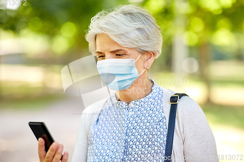 Image of old woman in medical mask with smartphone at park