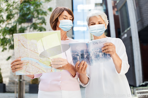 Image of senior women in masks with travel map in city