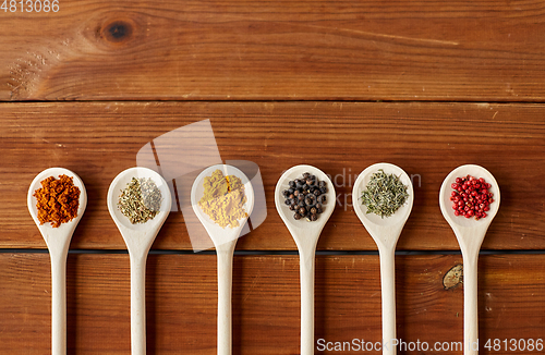 Image of spoons with different spices on wooden table