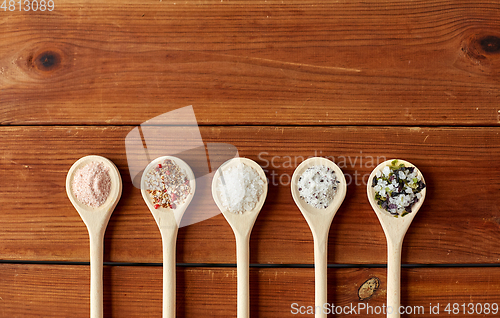 Image of spoons with salt and spices on wooden table