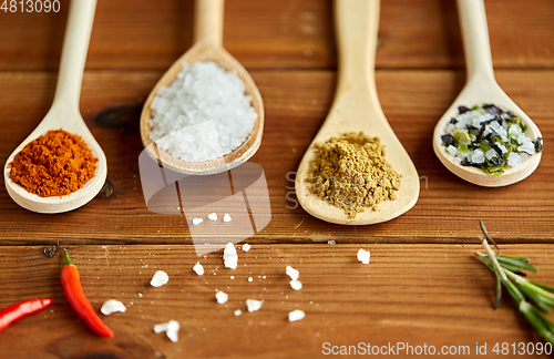 Image of spoons with spices and salt on wooden table