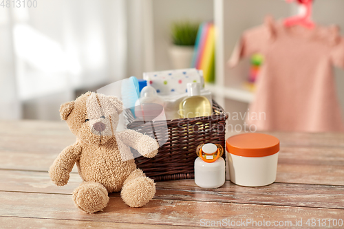 Image of baby things in basket and teddy bear toy on table