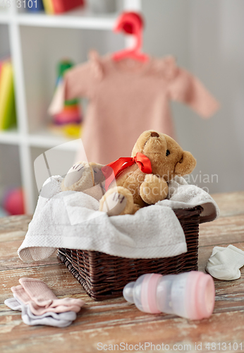 Image of teddy bear toy in basket with baby things on table