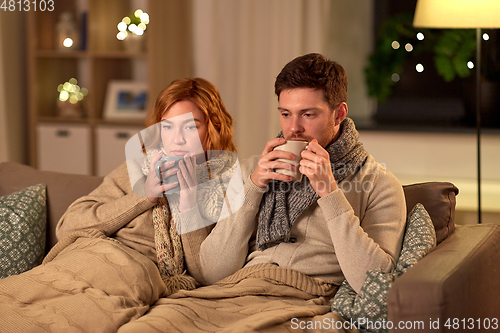 Image of sick young couple drinking hot tea at home