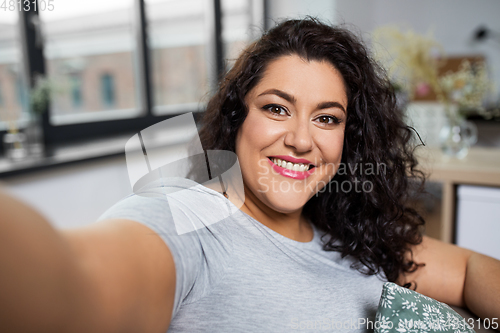 Image of happy smiling young woman taking selfie at home