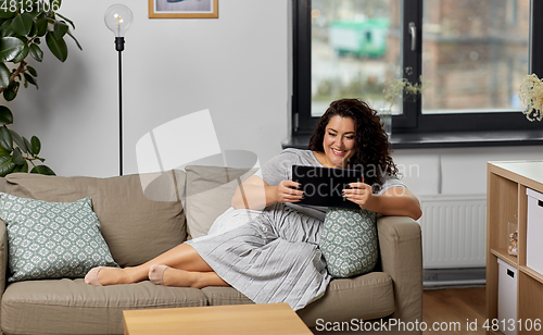 Image of woman with tablet pc computer on sofa at home